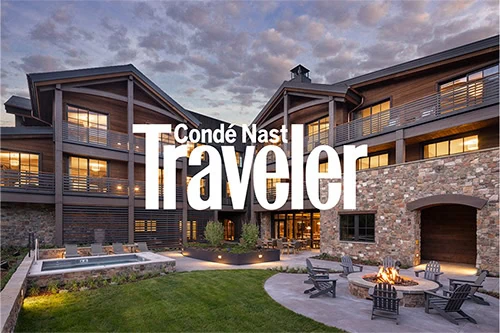 Conde Nast Traveler logo on a modern apartment complex exterior at dusk.