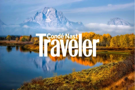 Condé Nast Traveler logo over a scenic landscape with mountains, trees, and a lake.