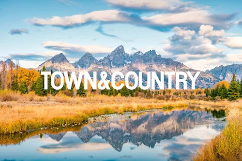 TOWN&COUNTRY text over mountain landscape with river reflection.
