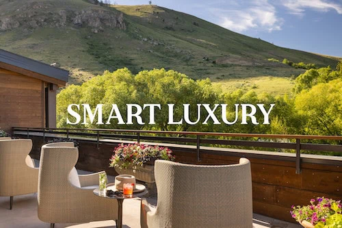 A comfortable outdoor seating area with a view of green hills and a wooden railing.