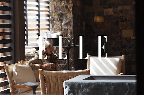 LELE logo on a wall in a cozy, modern interior with a woman sitting at a table.