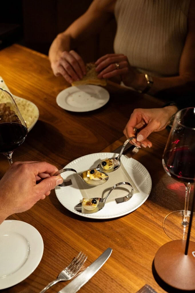 A woman serving appetizers on a white plate at a dinner table.