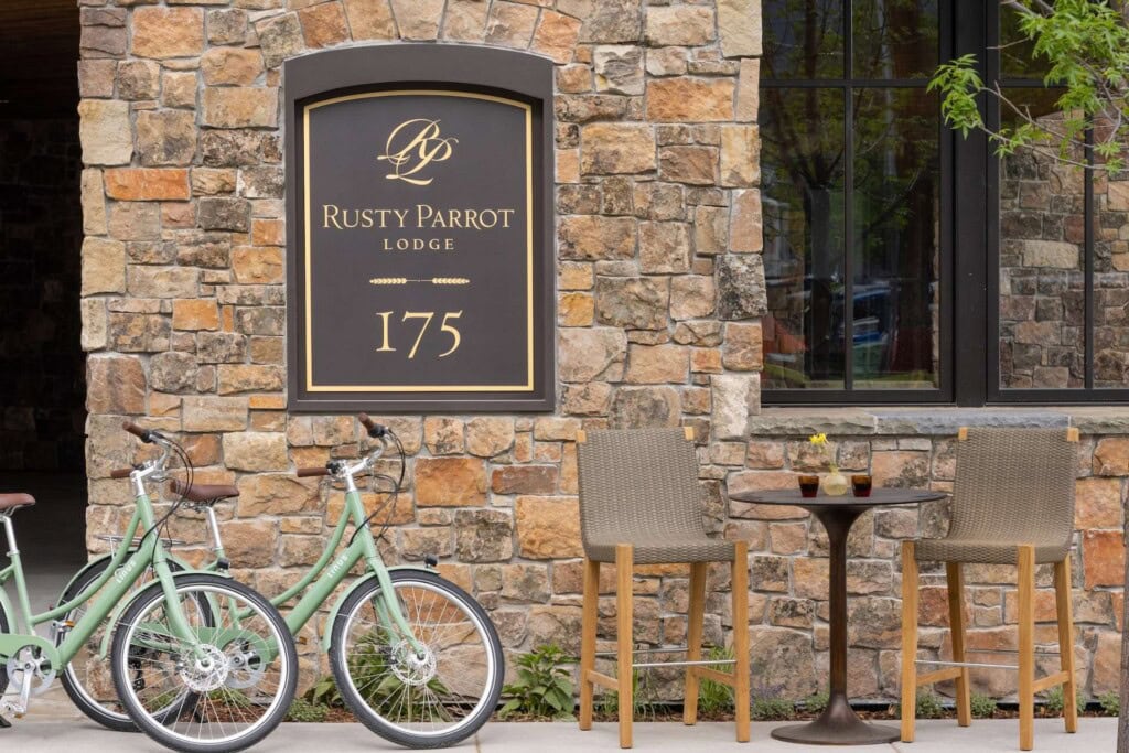 Rusty Parrot Lodge sign with two bicycles and outdoor seating area.