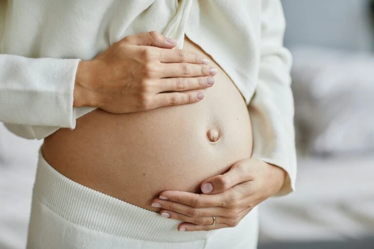 Pregnant woman holding her belly with both hands.
