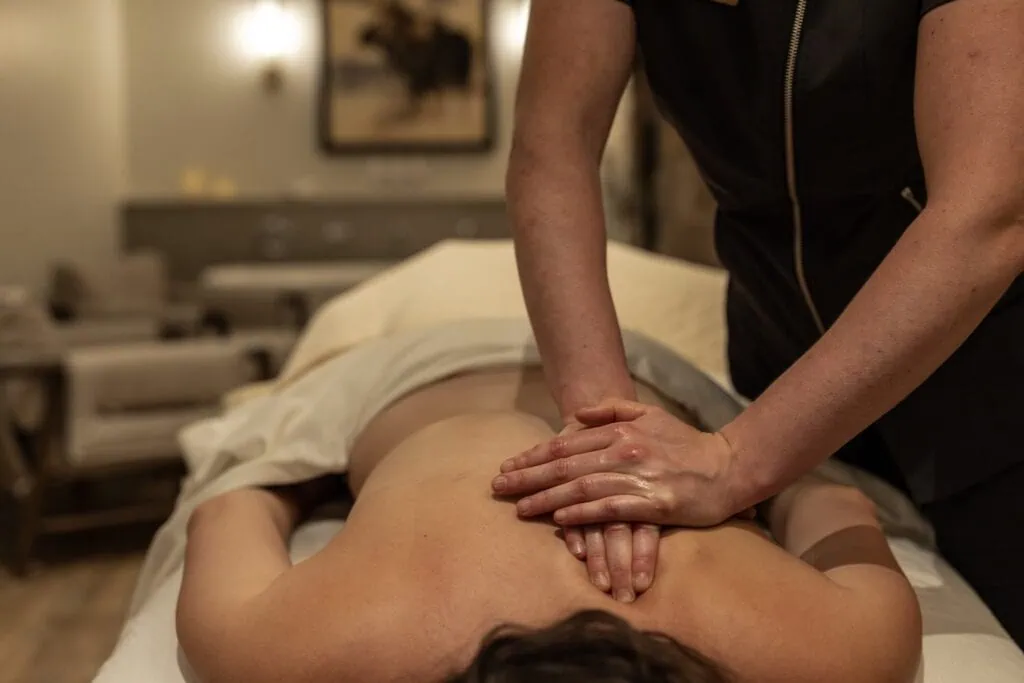 Massage therapist performing abdominal massage on a client lying face down.
