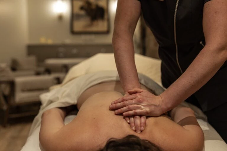 Massage therapist performing abdominal massage on a client lying face down.
