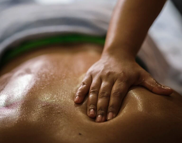 Person receiving a massage on their back with oil or lotion applied.