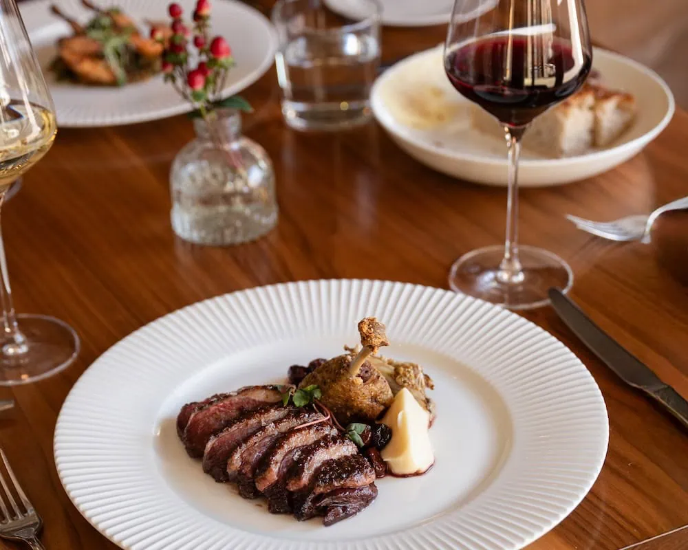 Steak with a small roasted chicken leg and a dollop of butter on a white plate.