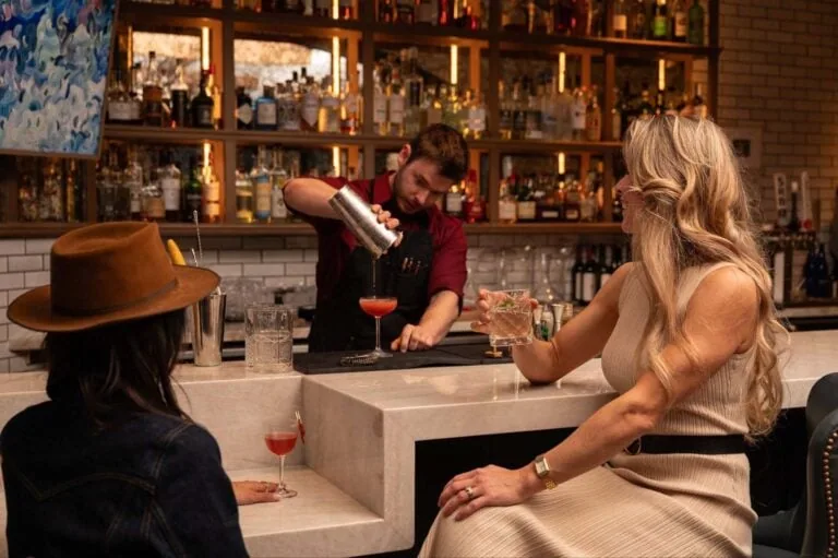 Bartender pouring a drink for a woman at the bar.