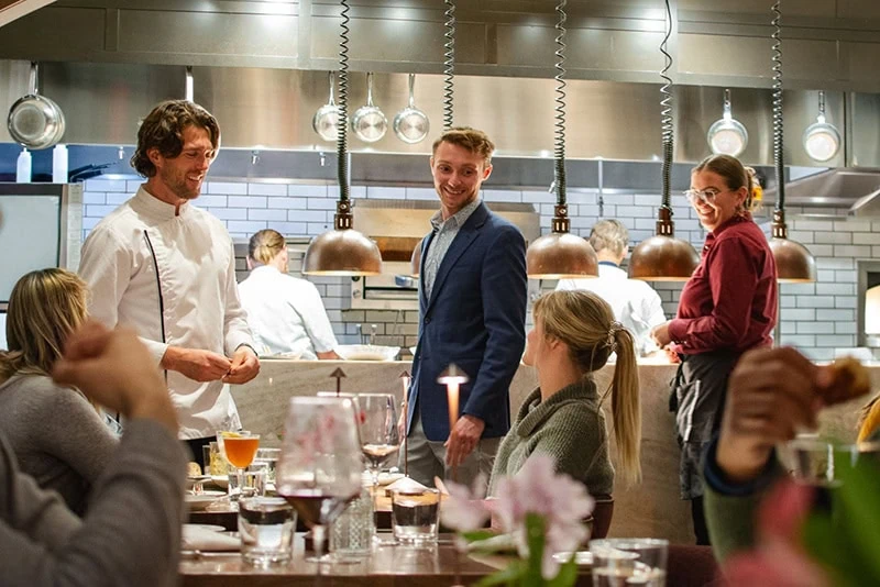 General Manager Matt Stone in a busy restaurant kitchen with staff and guests.