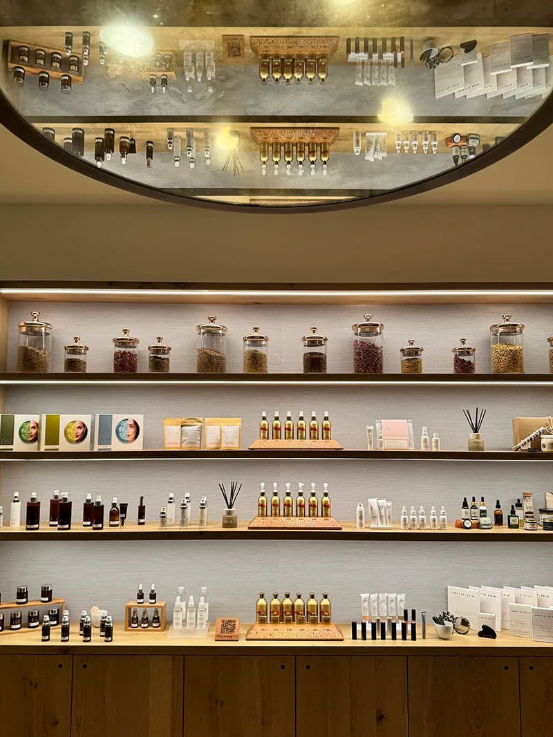 Shelves with various bottles and jars in a store, ceiling with reflective surface above.