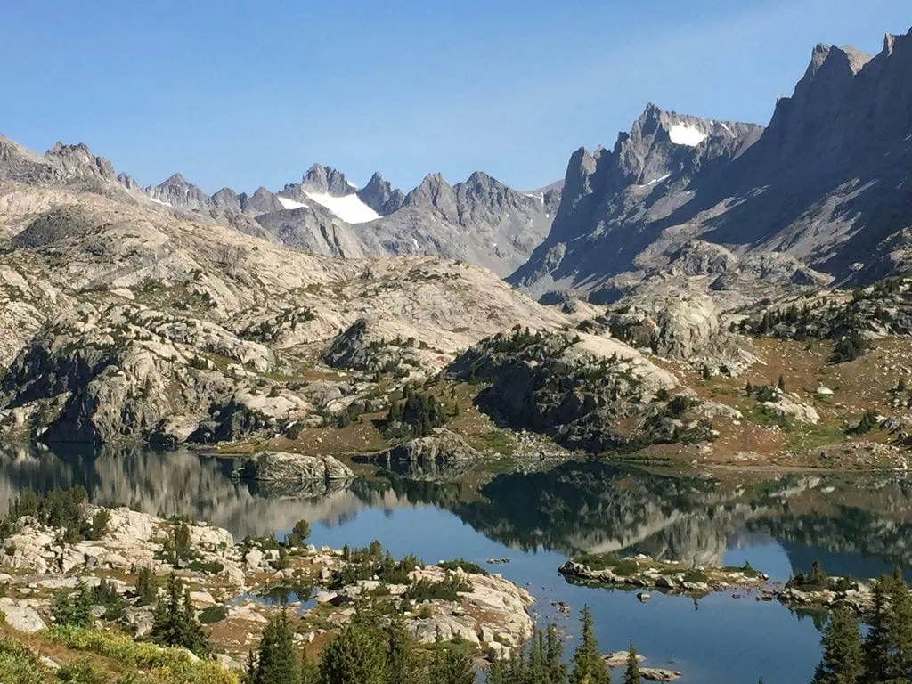 Mountain lake with rocky shores and snow-capped peaks in the background.