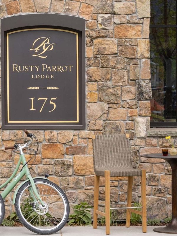 Rusty Parrot Lodge sign with two bicycles and outdoor seating area.