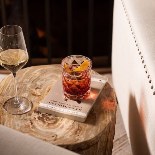 Two drinks on a wooden table next to a beige armchair.