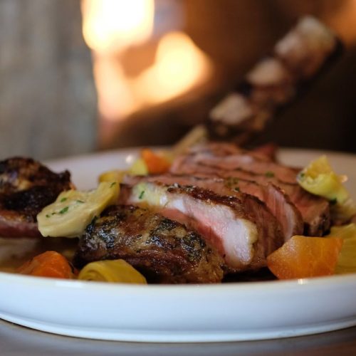 Grilled steak with vegetables on a white plate.