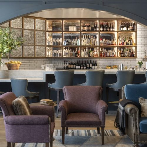 Bar area with shelves of bottles and seating at The Wild Sage Bar.