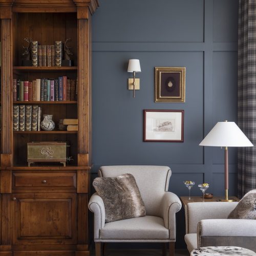 Cozy reading corner with armchair, bookshelf, and wall art in a blue room.